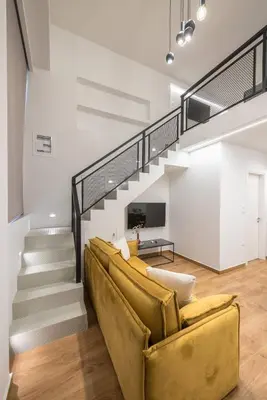 a living room with a yellow couch and stairs at Athens Loft in Athens