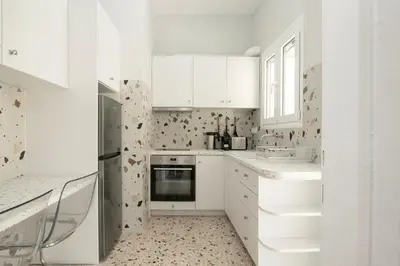a white kitchen with a sink and a refrigerator at Tsil House in Athens