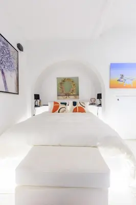 a white bedroom with a large white bed with orange pillows at Aiolos luxury apartment under acropolis in plaka in Athens