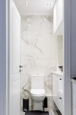 a white bathroom with a toilet and marble wall at Aiolos luxury apartment under acropolis in plaka in Athens