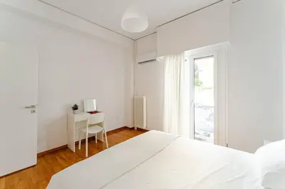 a white bedroom with a bed and a desk at George's Cozy 60m2 Apartment 7' Metro in Athens
