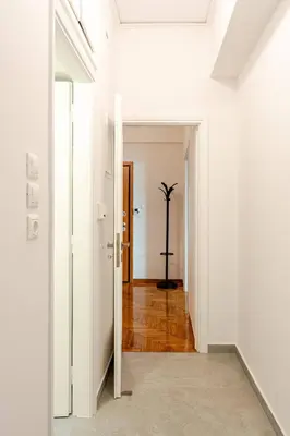 a hallway with white walls and a door with a plant at George's Cozy 60m2 Apartment 7' Metro in Athens