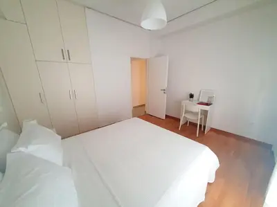 a white bedroom with a bed and a desk at George's Cozy 60m2 Apartment 7' Metro in Athens
