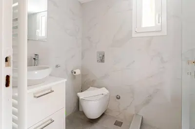 a white bathroom with a toilet and a sink at George's Cozy 60m2 Apartment 7' Metro in Athens