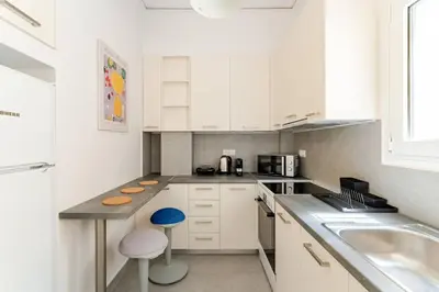 a white kitchen with a counter and a sink at George's Cozy 60m2 Apartment 7' Metro in Athens
