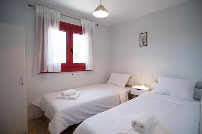 two beds in a white room with a window at Oregano peaceful complex in Porto Rafti