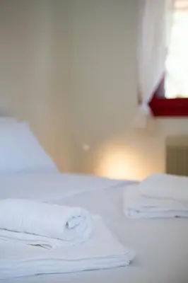 two white towels are stacked on a bed at Oregano peaceful complex in Porto Rafti