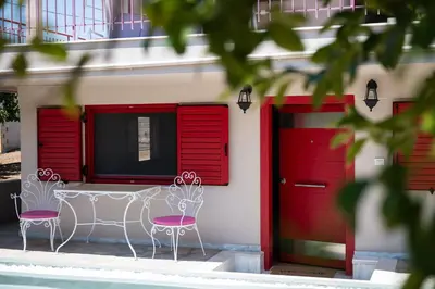 two chairs in front of a building with red doors at Oregano peaceful complex in Porto Rafti