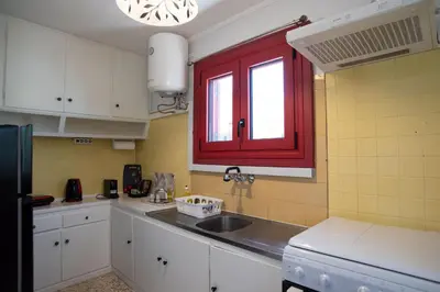 a kitchen with a sink and a red window at Oregano peaceful complex in Porto Rafti