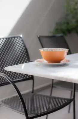an orange bowl sitting on a table with a chair at The Meta Stay - Backyard Oasis with Rooftop Access in Athens