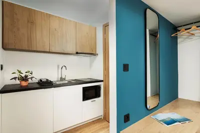 a kitchen with white cabinets and a blue wall at The Meta Stay - Backyard Oasis with Rooftop Access in Athens