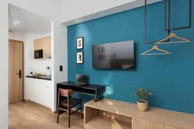 a room with a desk and a tv on a blue wall at The Meta Stay - Sunny Retreat with Rooftop Access in Athens