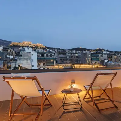 two chairs and a table on a balcony with a city at The Meta Stay - Sunny Retreat with Rooftop Access in Athens