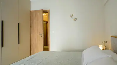a bedroom with a white bed and a wooden door at Charming apartment Galatsi for 5 by MPS in Athens