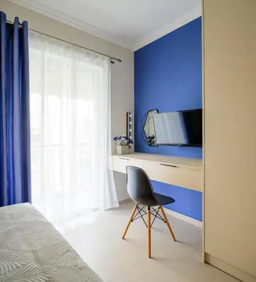 a bedroom with a blue accent wall and a chair at Charming apartment Galatsi for 5 by MPS in Athens