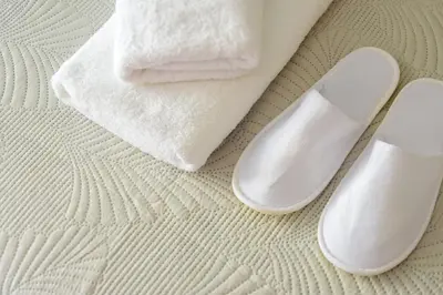 a pair of white slippers and towels on a bed at Charming apartment Galatsi for 5 by MPS in Athens