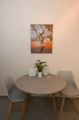 a table with chairs and a painting on the wall at Elida Inn Near ATH Airport in Markopoulo