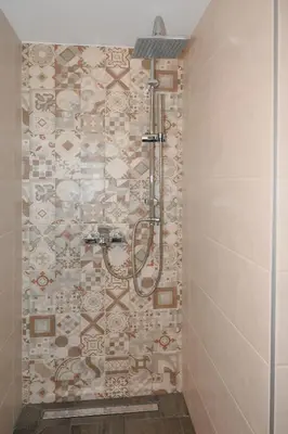 a shower in a bathroom with a tile wall at Elida Inn Near ATH Airport in Markopoulo