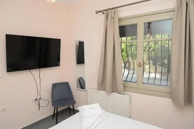 a bedroom with a tv and a chair and a window at Elida Inn Near ATH Airport in Markopoulo