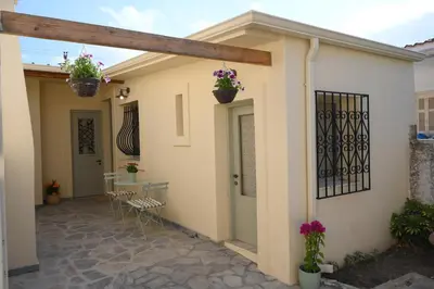 a patio with chairs and potted plants on a house at Elida Inn Near ATH Airport in Markopoulo