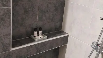 a bathroom with a shower with two complimentary products on a shelf at Miranda's Apartment Koukaki in Athens