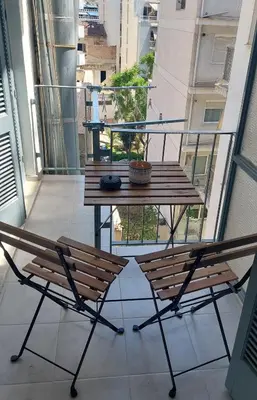 a table and two chairs on a balcony with a table at Miranda's Apartment Koukaki in Athens