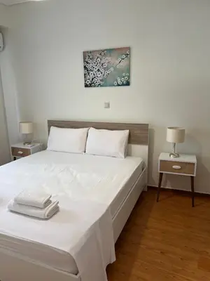 a bedroom with a bed with white sheets and two tables at Acropolis Sidewalk view in Athens