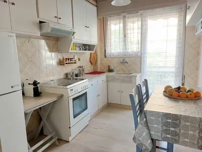 a kitchen with white cabinets and a table with a bowl of fruit at Φωτεινό δίκλινο δωμάτιο με θέα! in Athens