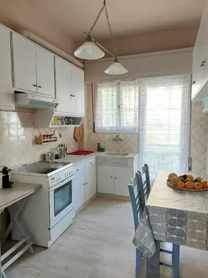 a kitchen with white cabinets and a table with a bowl of fruit at Δωμάτιο για χαλάρωση με θέα in Athens