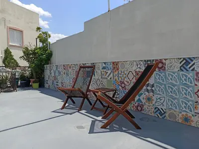 two chairs sitting next to a wall with tiles at Terrace holiday studio apartment in Athens