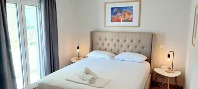 a bedroom with a white bed with two tables and a window at Best Acropolis museum apartment in Athens