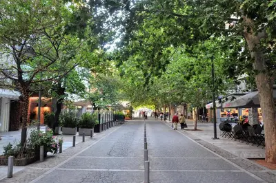 a street with trees and people walking down the street at Best Acropolis museum apartment in Athens