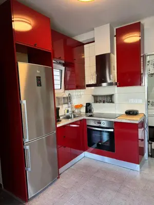 a kitchen with red cabinets and a stainless steel refrigerator at Studio pellinis in Athens