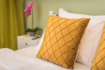 a bed with white sheets and a gold pillow at Top Ten Apartment 3 in Athens