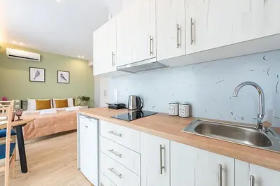 a kitchen with white cabinets and a sink and a couch at Top Ten Apartment 3 in Athens
