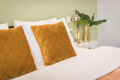 a bed with white sheets and brown pillows on it at Top Ten Apartment 3 in Athens