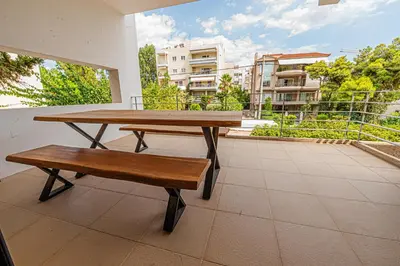 a wooden table and a bench on a balcony at Stylish Escape in Glyfada in Athens