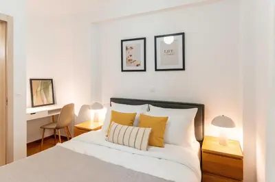 a bedroom with a bed with two lamps and a desk at Phaedrus Living Alimos Edem Beach Flat in Athens