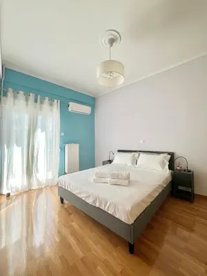 a bedroom with a large bed with blue walls and wooden floors at Cozy 3BRs Family Haven near Metro&Acropolis in Athens