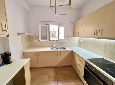 a kitchen with white cabinets and a sink and a window at Cozy 3BRs Family Haven near Metro&Acropolis in Athens
