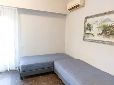 a bedroom with two beds and a painting on the wall at Γωνιακό φωτεινό δωμάτιο in Athens
