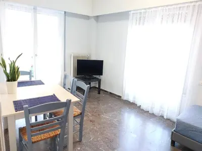 a dining room with a table and chairs and a television at Γωνιακό φωτεινό δωμάτιο in Athens