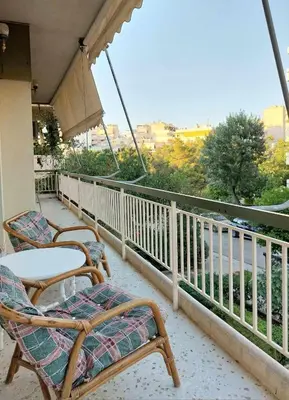 a balcony with chairs and a table and an umbrella at Γωνιακό φωτεινό δωμάτιο in Athens