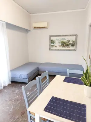 a room with two beds and a table and chairs at Γωνιακό φωτεινό δωμάτιο in Athens