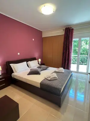 a bedroom with a large bed with a red wall at Comfortable apartment at skouze hill in Athens