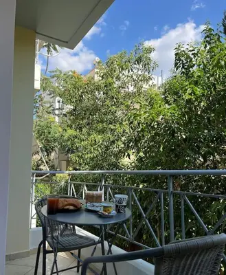 a table and two chairs on a balcony at Comfortable apartment at skouze hill in Athens