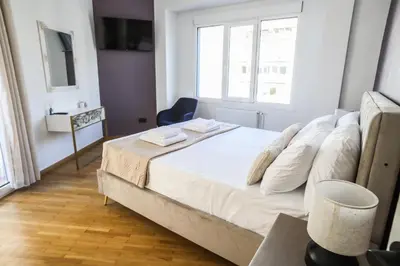 a bedroom with a bed with white sheets and a window at 3BD apartment with Acropolis & Temple of Zeus view in Athens