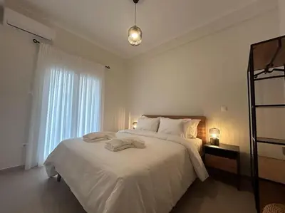a white bedroom with a large bed and a window at Urban Escape in Athens