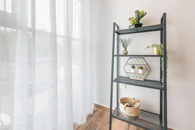 a black shelf with plants in a room with a window at Top Ten Apartment 4 in Athens