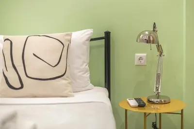 a bed with a pillow and a lamp on a table at Athens Stay in Athens
